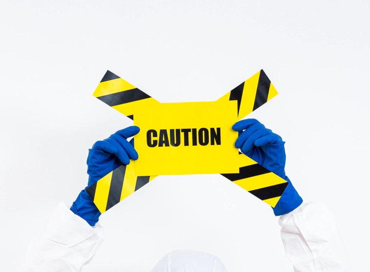worker with blue gloves and white jumpsuit with a caution sign